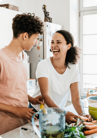 Une femme et un homme rient ensemble dans une cuisine, créant une atmosphère joyeuse et conviviale