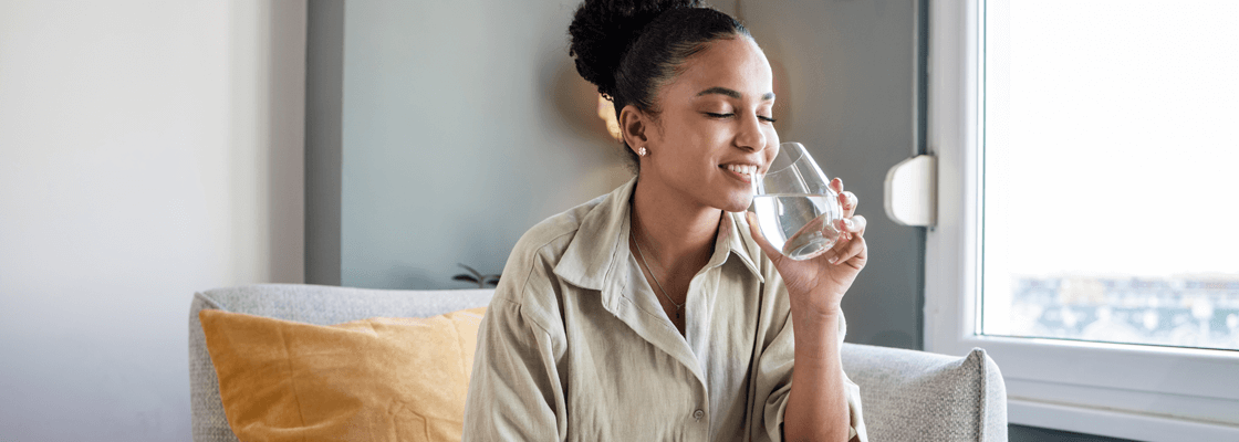 Femme sur un canapé, savourant un verre d'eau